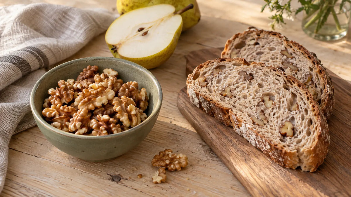 Walnussstücke und -hälften in einer Schale mit Walnussbrot und Birne im Hintergrund.